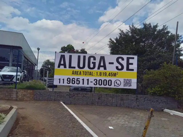 Banner de lona com anúncio de locação instalado em área externa.