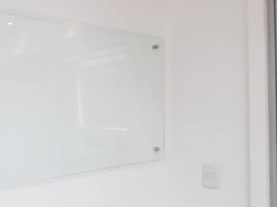 Quadro de vidro branco sob medida fixado em parede.