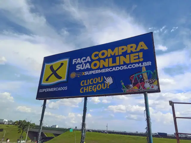 Outdoor com lona publicitária recém-instalada em área aberta.